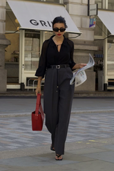 a lady in a black silk shirt and a pair of grey pants